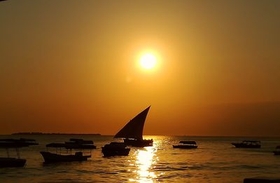 Silhouette sailboats in sea against sky during sunset