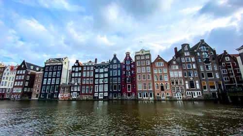 Buildings by river against sky