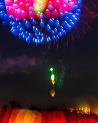 Low angle view of illuminated balloons against sky at night