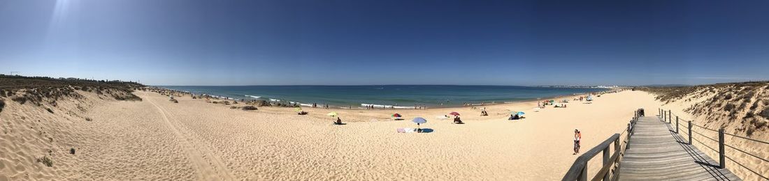Panoramic view of people on beach against sky