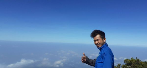 Portrait of smiling man standing against cloudscape