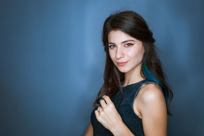 Close up shot of stylish young brunette woman with blue strands of hair smiling