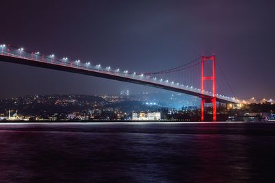 Illuminated bridge in city against sky at night