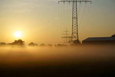 Silhouette electricity pylon against sky during sunset