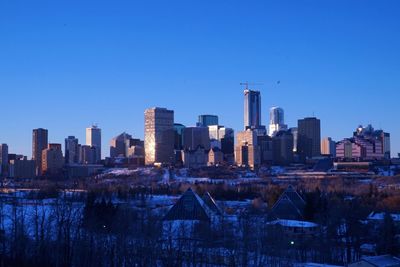 Modern buildings in city against clear blue sky