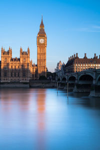 Arch bridge over river against buildings and sky in city