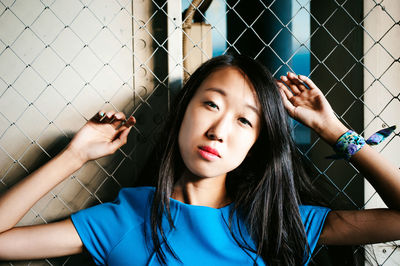 Close-up portrait of woman standing by chainlink fence