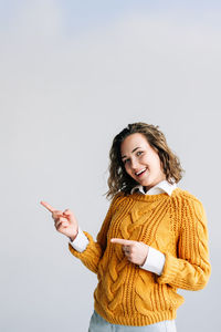 Portrait of young woman standing against white background