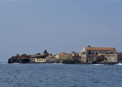 Buildings by sea against clear blue sky