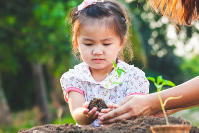 Close-up of girl holding plant in hand with mother outdoors