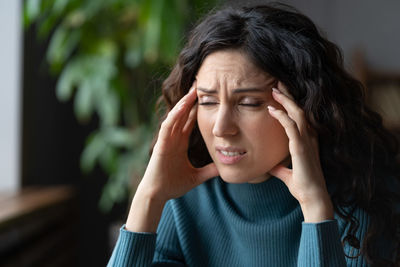 Fatigued overworked young woman suffering from migraine, worrying about personal problems