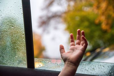 Close-up of hand on car window