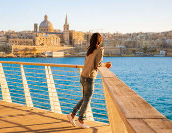 Side view of young woman standing against sea