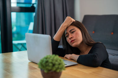 Young woman using phone while sitting on table