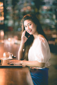 Portrait of a smiling young woman at table