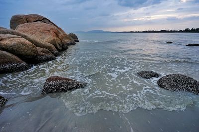 Scenic view of rocks on beach against sky