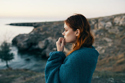 Young woman standing on rock by sea