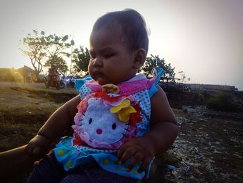 Cute boy holding baby while sitting against sky