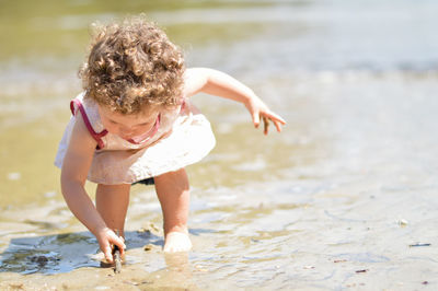 Girl playing with stick in muddy water