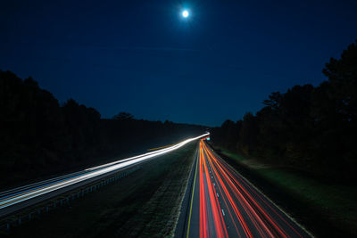 Light trails on road against sky at night