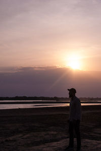 Man standing on beach against sky during sunset