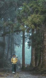 Rear view of woman standing by trees