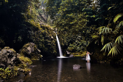 Woman standing by waterfall in forest