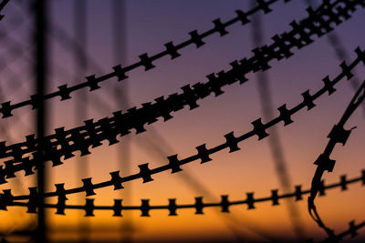 Low angle view of barbed wire against sky at dusk