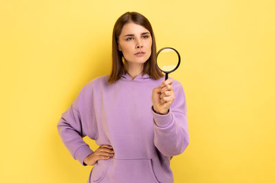 Midsection of woman holding stethoscope against yellow background