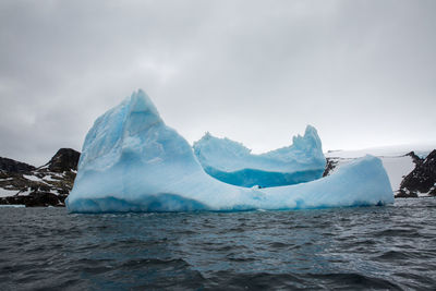 Scenic view of iceberg floating on sea against sky