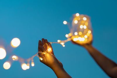 Hand hold bottle ,selective soft focus on light bulb with foreground and background bokeh on sky