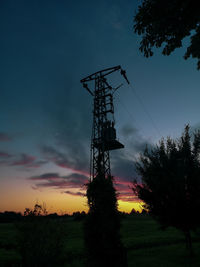 Low angle view of silhouette communications tower against sky during sunset