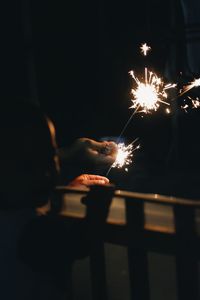 Cropped hand holding sparkler at night