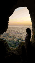 People standing on rock formation at sunset