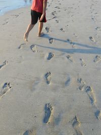 Low section of boy walking on sand at beach