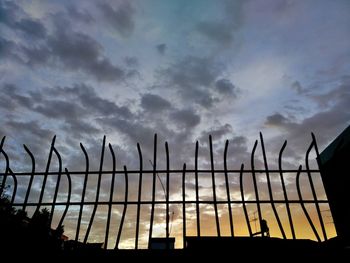 Low angle view of silhouette fence against sky during sunset