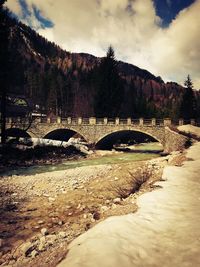 Arch bridge over river against sky