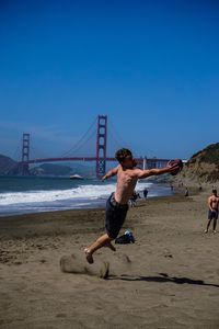 Shirtless man playing with volleyball at beach