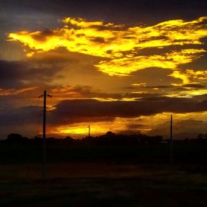 Scenic view of landscape against cloudy sky at sunset