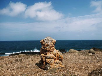 Rock on beach against sky
