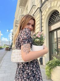 Low angle view of young woman standing by plants