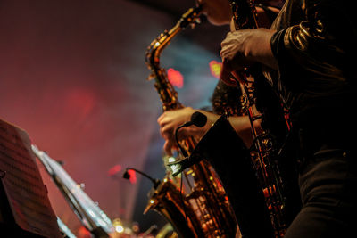 Midsection of men playing saxophones in concert