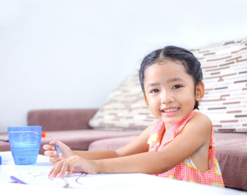 Portrait of cute girl drawing at table in home