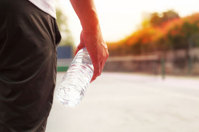 Close-up of hand holding water bottle outdoors