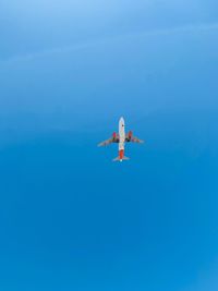 Low angle view of airplane flying against clear blue sky