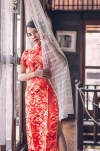 Full length of woman standing against red wall