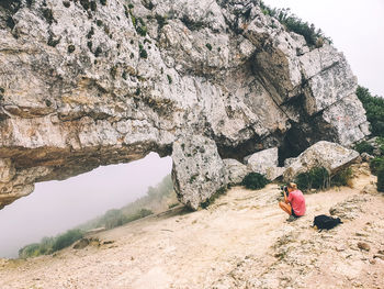 Female hiker taking photos next to the rock