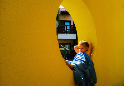 Boy looking away against yellow wall