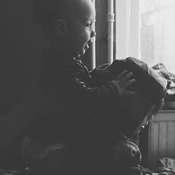 Side view of boy looking through window at home