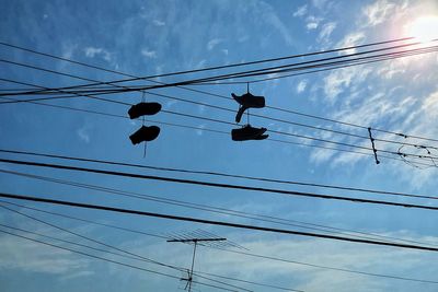 Low angle view of silhouette power lines against sky